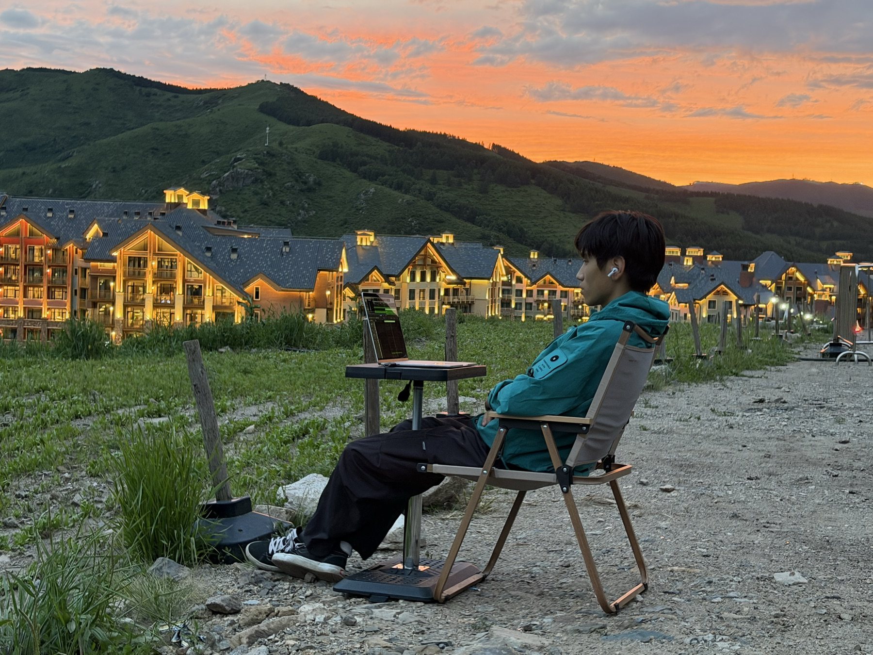 齐恩贺在山间夕阳下使用电脑